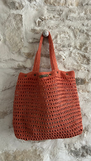 Sac cabas bohème en crochet corail détail suspendu mur pierre